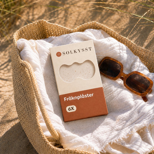 Solkysst Fräknplåster i en strandkorg med solglasögon